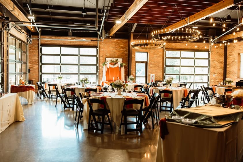 Wedding reception setup with round tables and glass doors inside the Little Miami Brewing Company Event Center.