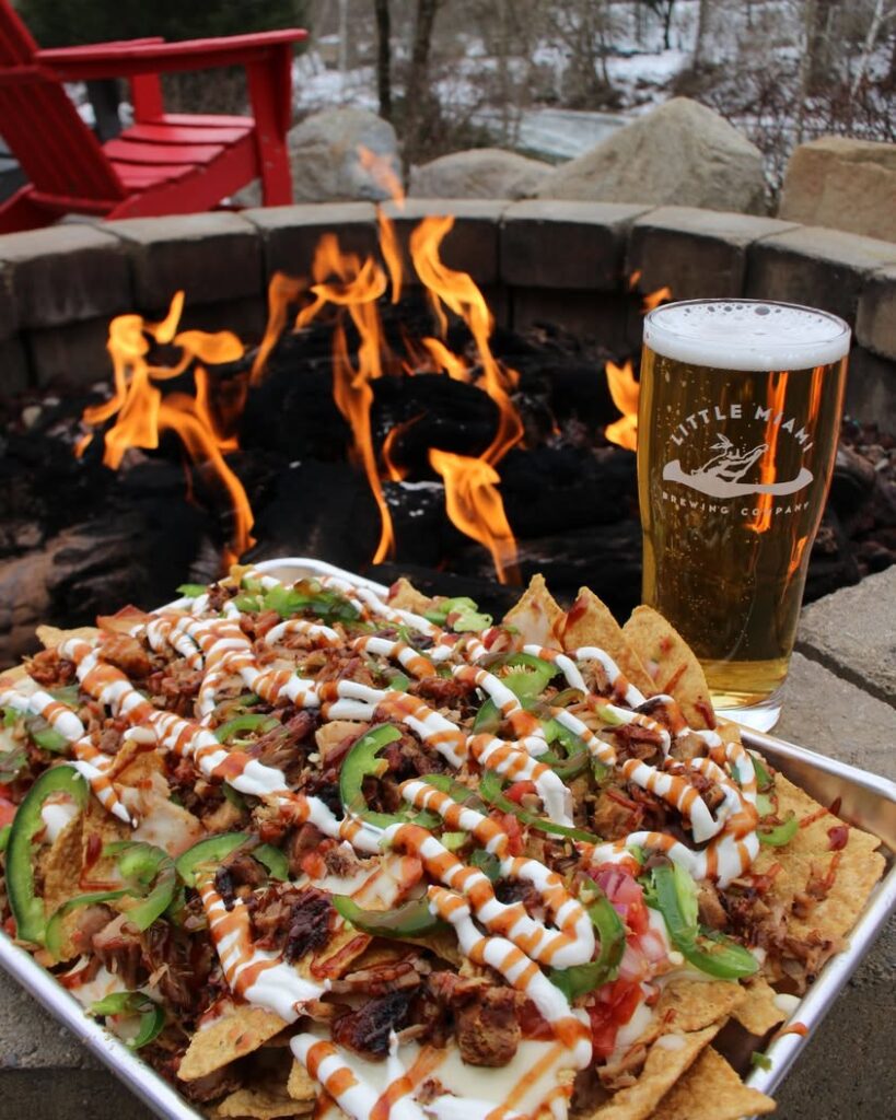 Little Miami Brewing Company’s Pig Skin Nachos served with an ice-cold beer at the riverside firepit, perfect for an evening by the water.