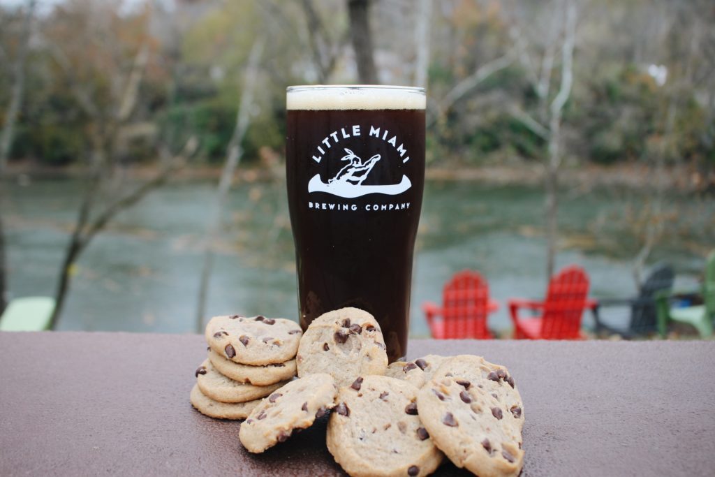 Little Miami Brewing Company’s Earth Cookie Brown Ale on a table with cookies, highlighting its chocolate and coffee-inspired flavors.