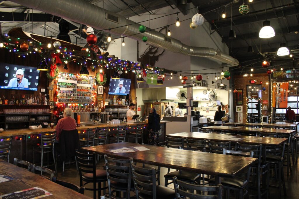 Little Miami Brewing Company taproom decorated for Christmas with string lights, ornaments, and a warm, festive atmosphere.
