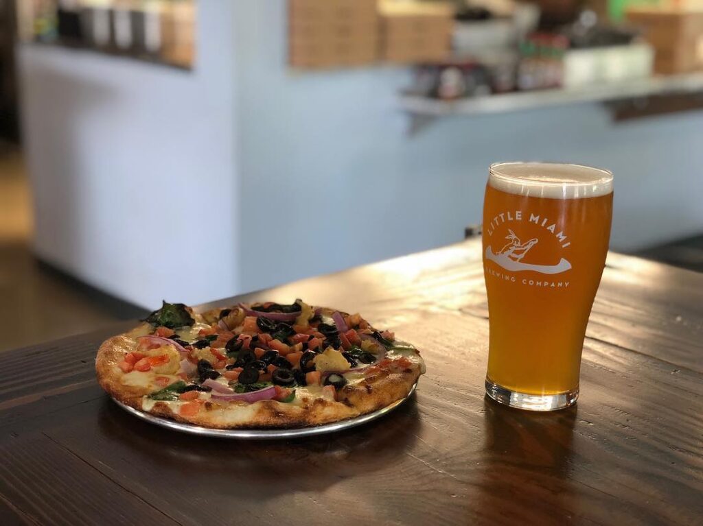 Little Miami Brewing Company’s Harvest Moon IPA paired with a fresh pizza on a table at the taproom.