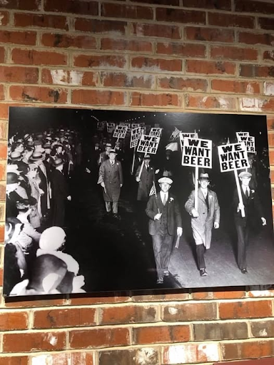 Vintage Prohibition-era protest scene featuring “We Want Beer” signs displayed on a brick wall at Little Miami Brewing Company.