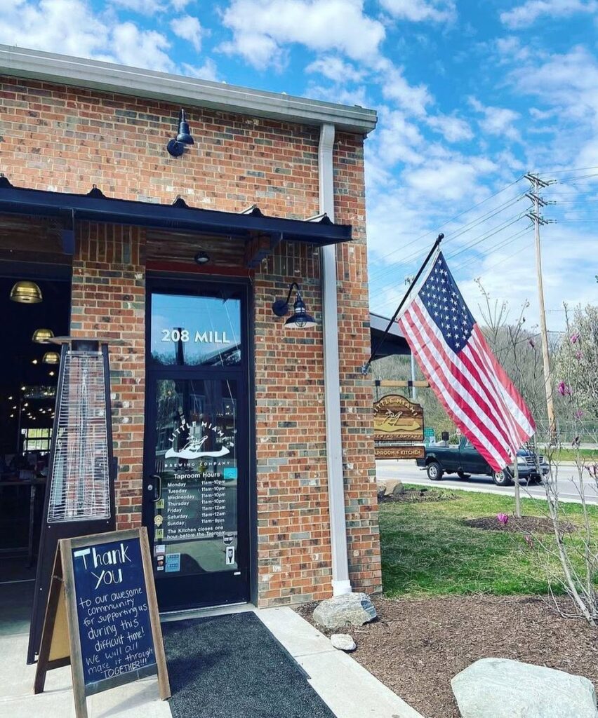 Exterior of Little Miami Brewing Company in Historic Old Milford featuring a brick facade, American flag, and welcoming community atmosphere.