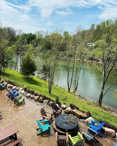 Colorful outdoor patio with Adirondack chairs and a fire pit overlooking the Little Miami River at Little Miami Brewing Company.