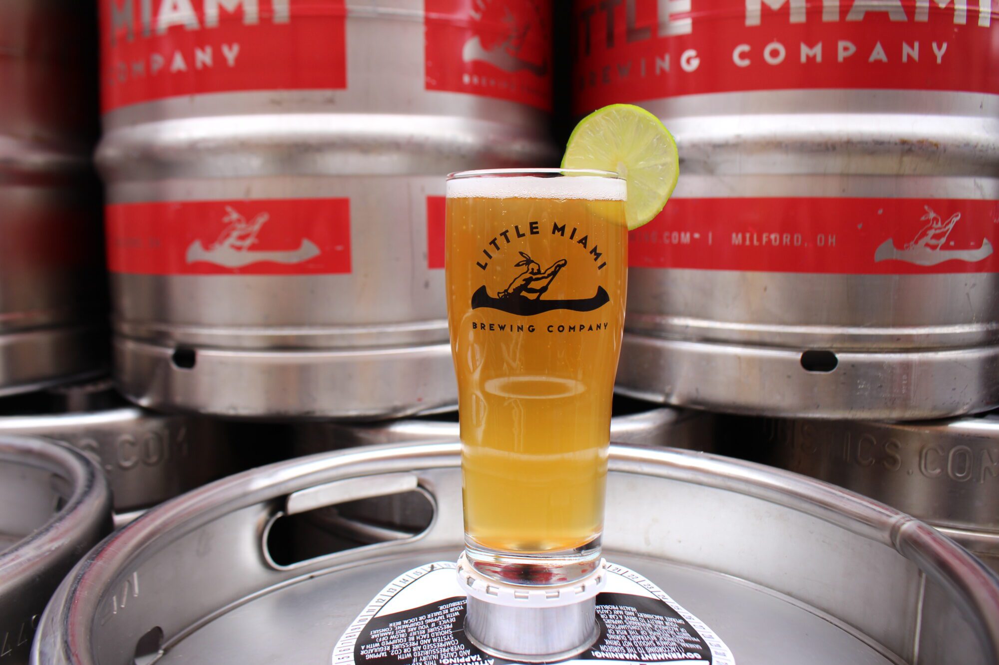 Glass of amber beer from Little Miami Brewing Company resting on a stainless steel beer keg.