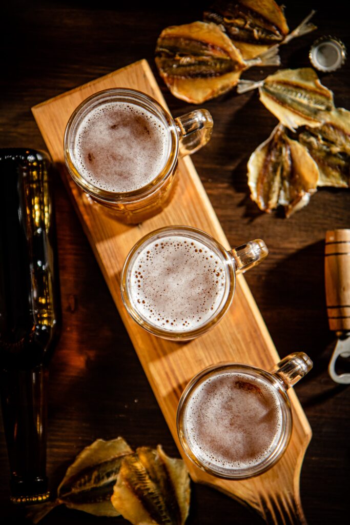 Three beers on a board with dried fish and a bottle opener. This could be a beer flight from breweries in Cincinnati .