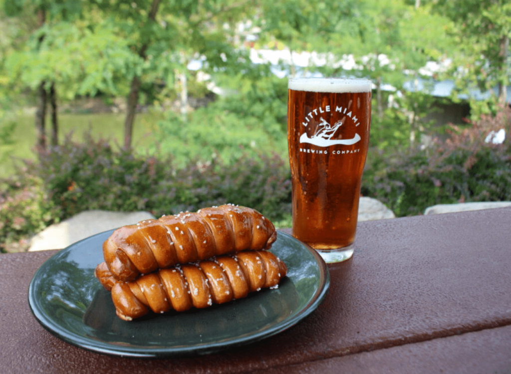 A Little Miami Brewing Company beer and pretzels on a table. This brewery is a great option for brewery trips near you.