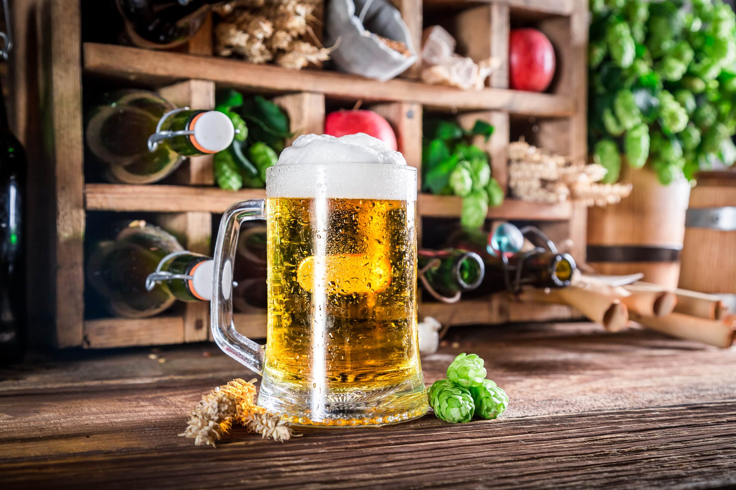 A frosty beer mug with fresh hops and wheat, capturing the essence of breweries in Cincinnati. Rustic shelves of bottles and ingredients in the background.