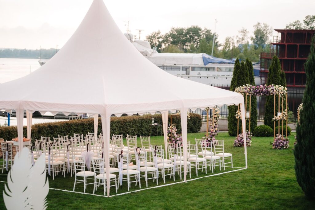 Elegant tented setup by the water, ideal for outdoor wedding venues with picturesque views and charming floral decor.