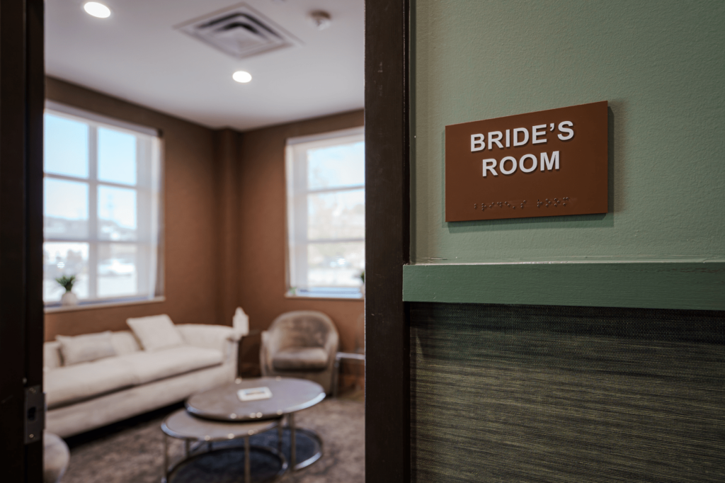 A sign above a door reads "Bride's Room." The room is part of a reception venue and is decorated with neutral colors and soft lighting.