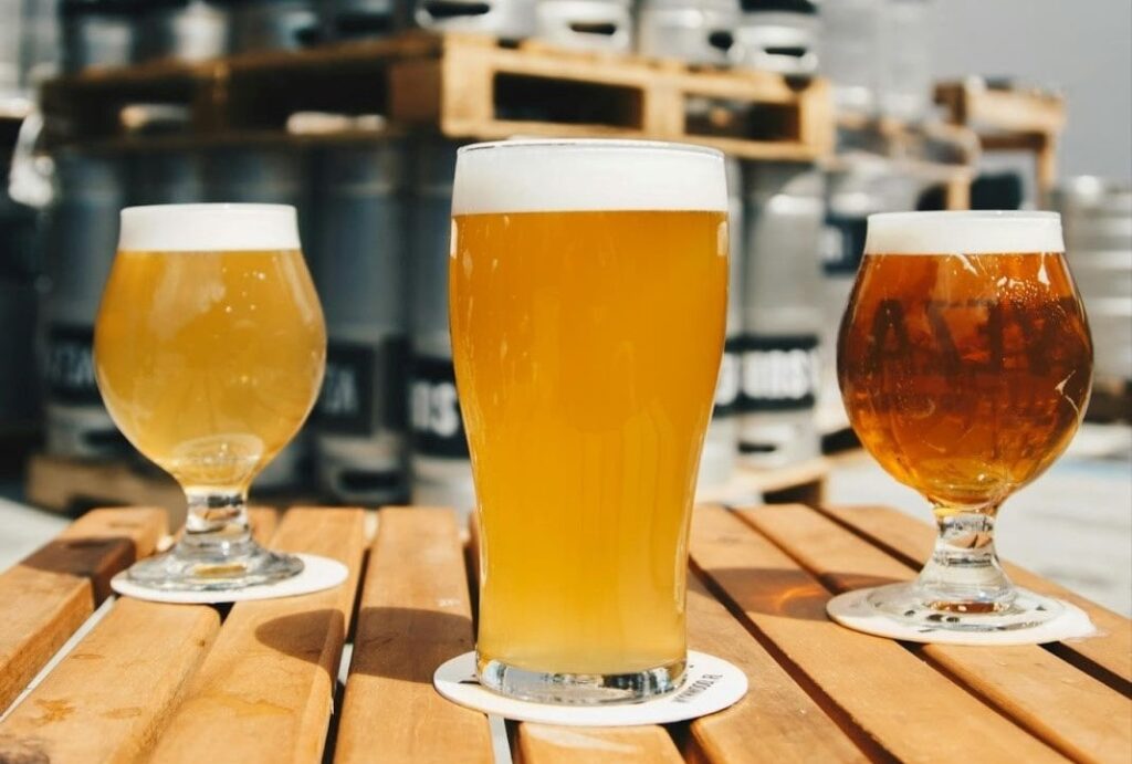 Three glasses of different flavored beers on a wooden table.