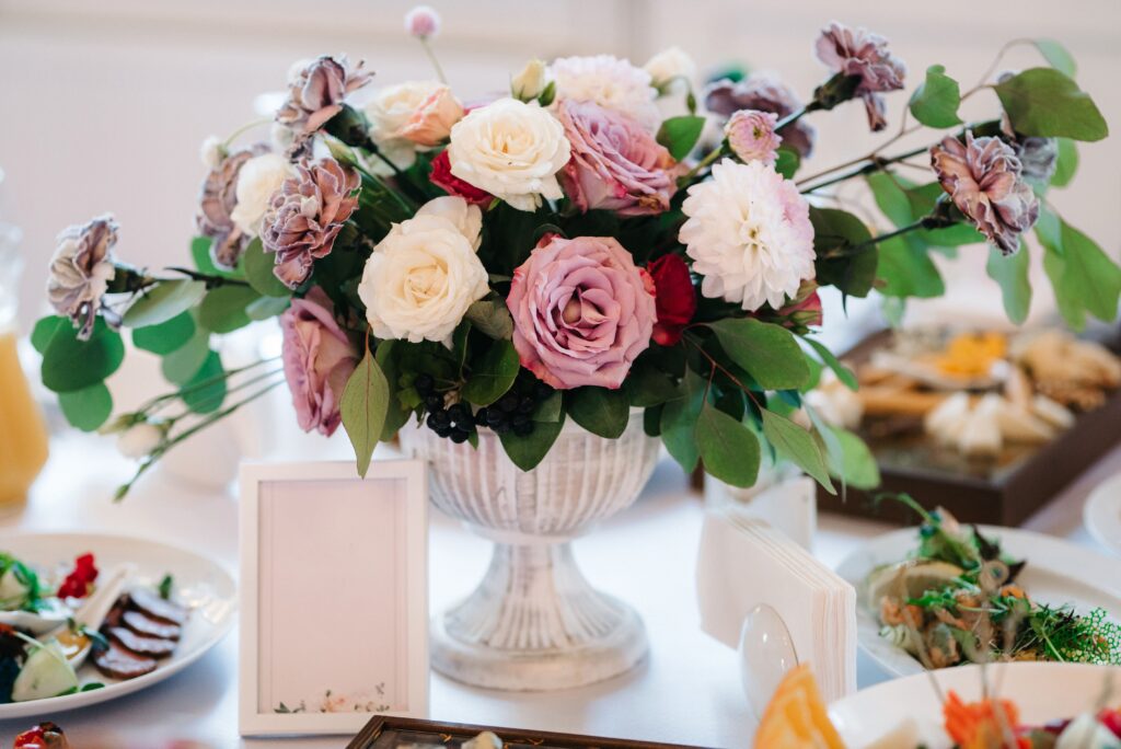 Elegant floral arrangements featuring pastel roses, white blooms, and lush greenery in a classic vase, perfect for wedding centerpieces.