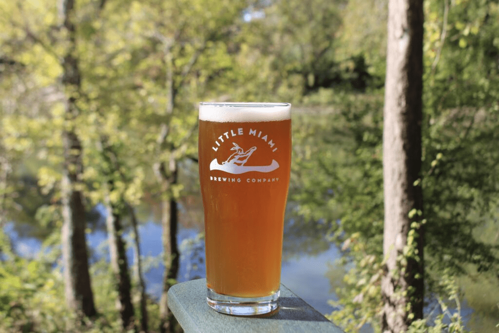 A glass of IPA from Little Miami Brewing Company, surrounded by lush greenery, perfect for enjoying outdoors.