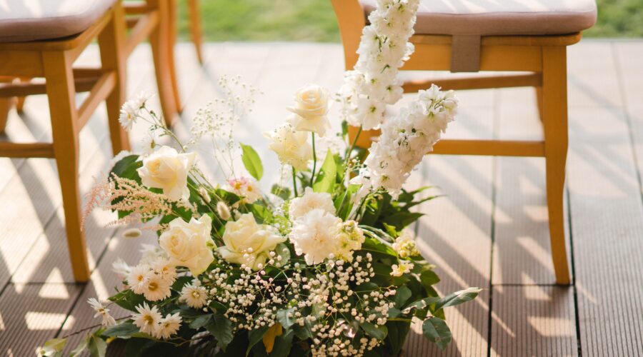 A delicate floral arrangements featuring white roses, baby's breath, and greenery, perfect for wedding aisle decor.