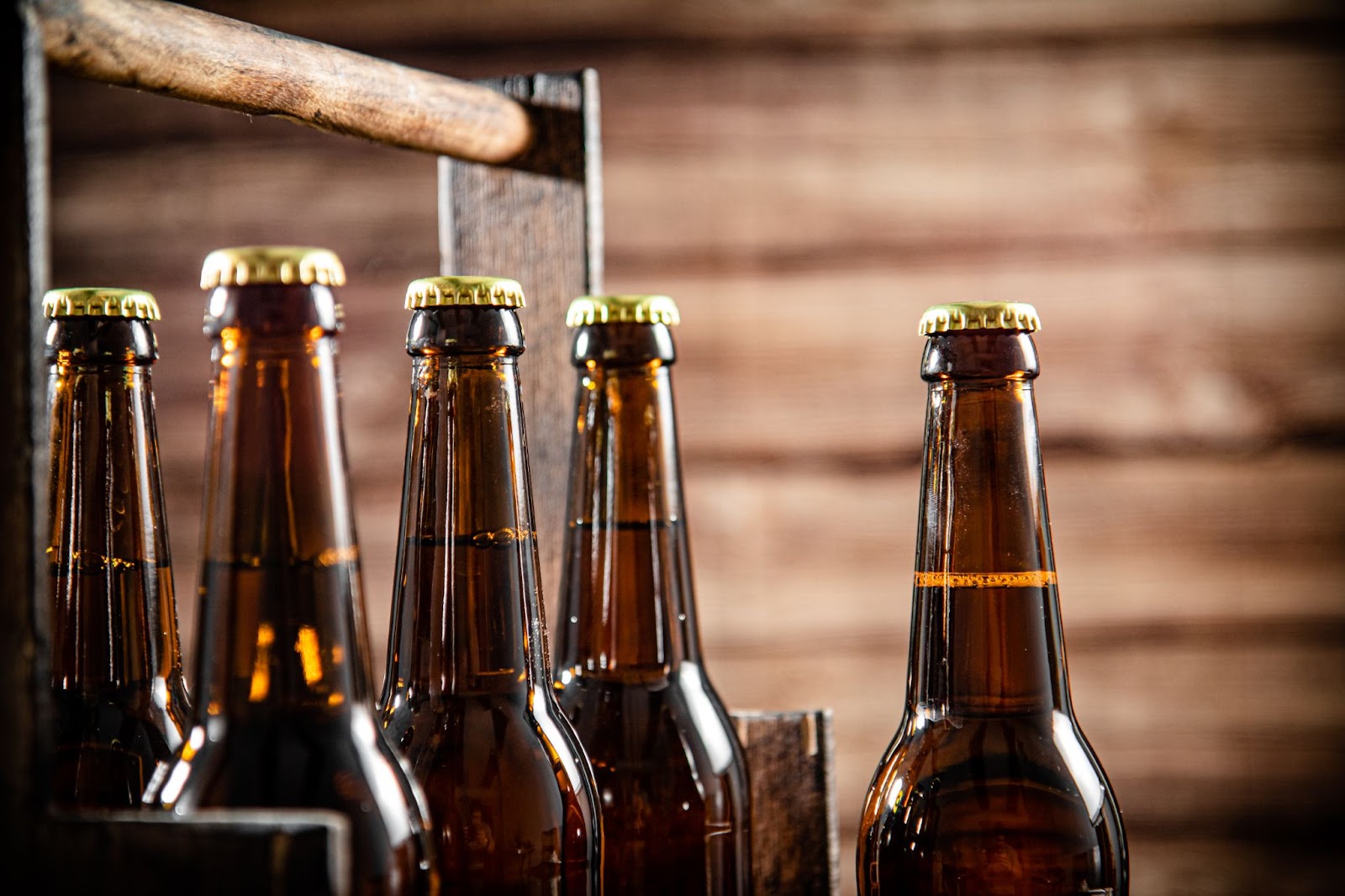 A close-up of a wooden crate filled with amber-colored beer bottles, showcasing the craftsmanship of a local microbrewery.