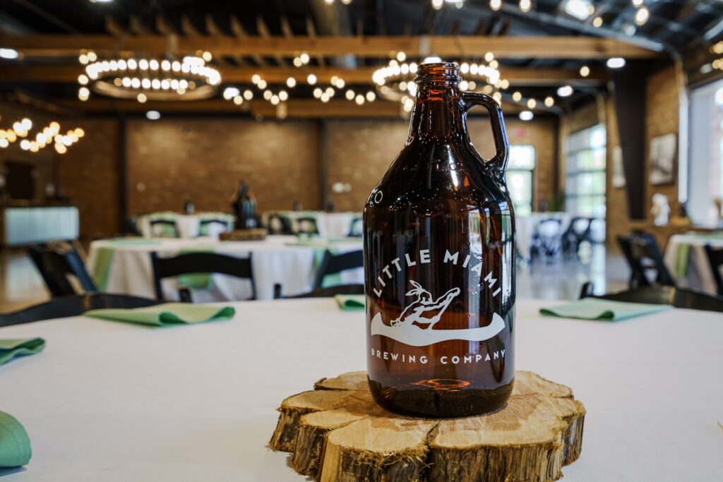 A growler from Little Miami Brewing Company sits on a wooden slice as a centerpiece on a table at the craft brewery.