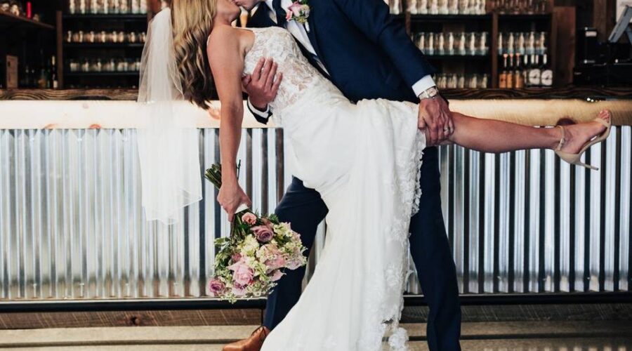 Bride and groom sharing a romantic moment in front of a stylish bar setup at stunning wedding venues.