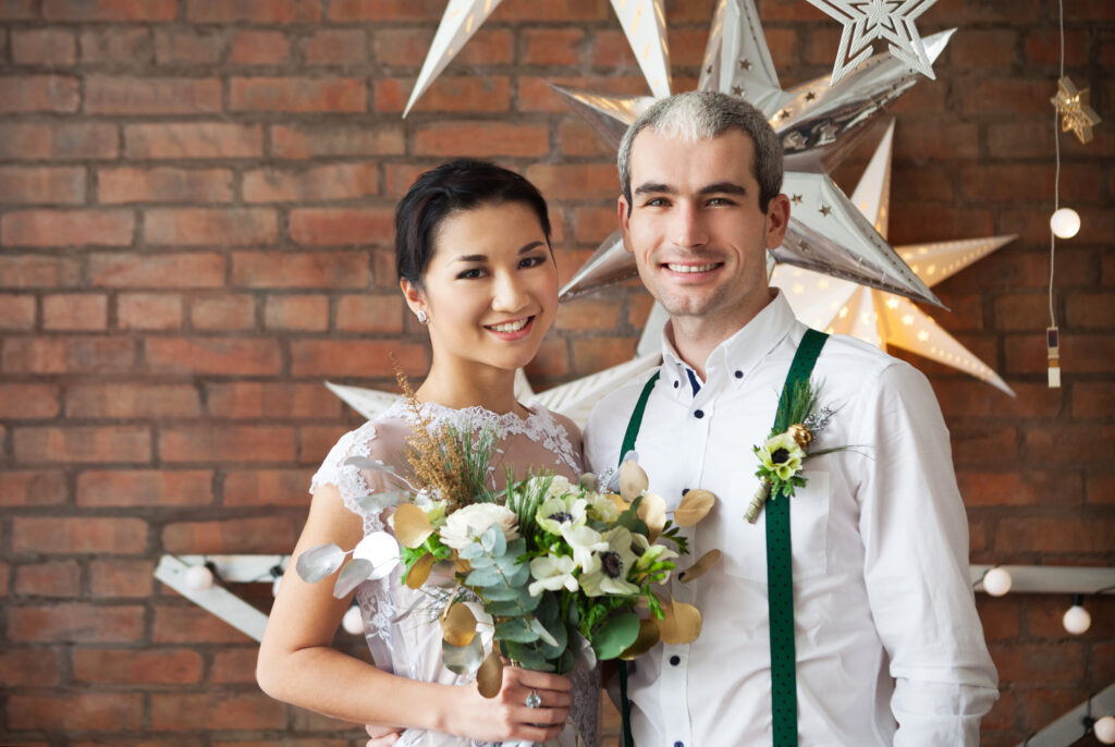 Couple posing at a brewery wedding decorated with creative wedding themes, featuring rustic brick walls and star-shaped lights.