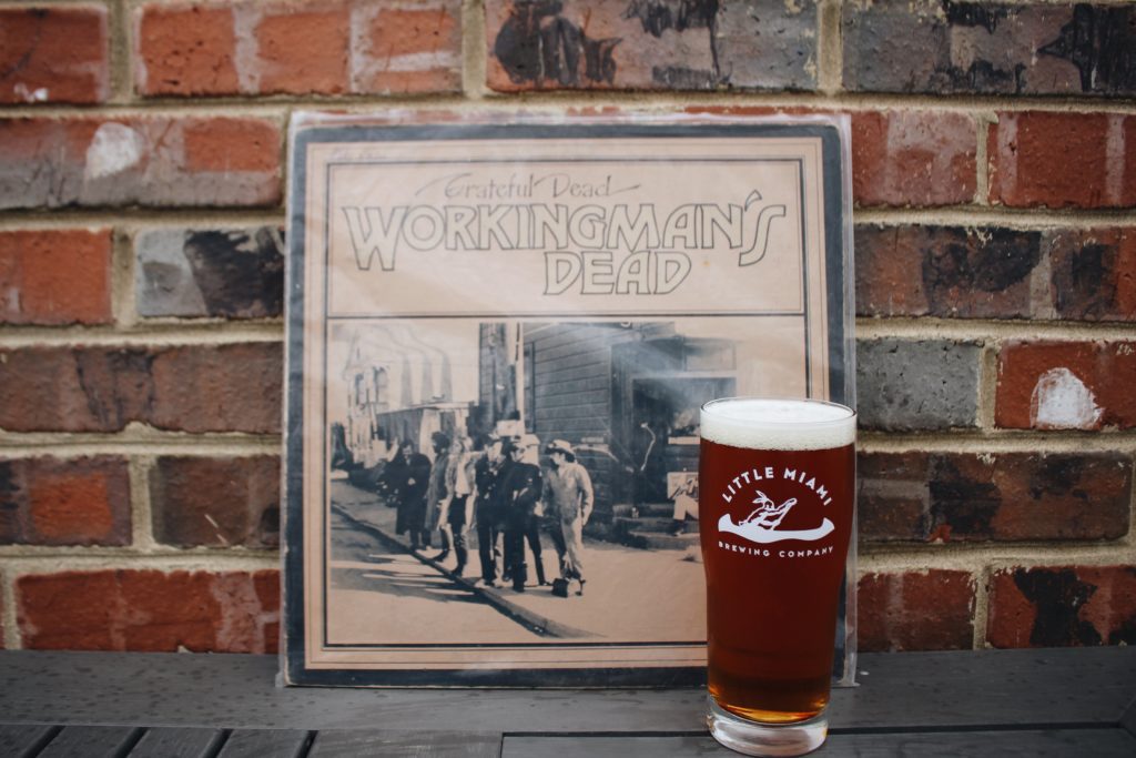 Little Miami Brewing Company beer glass next to Grateful Dead's "Workingman's Dead" album.