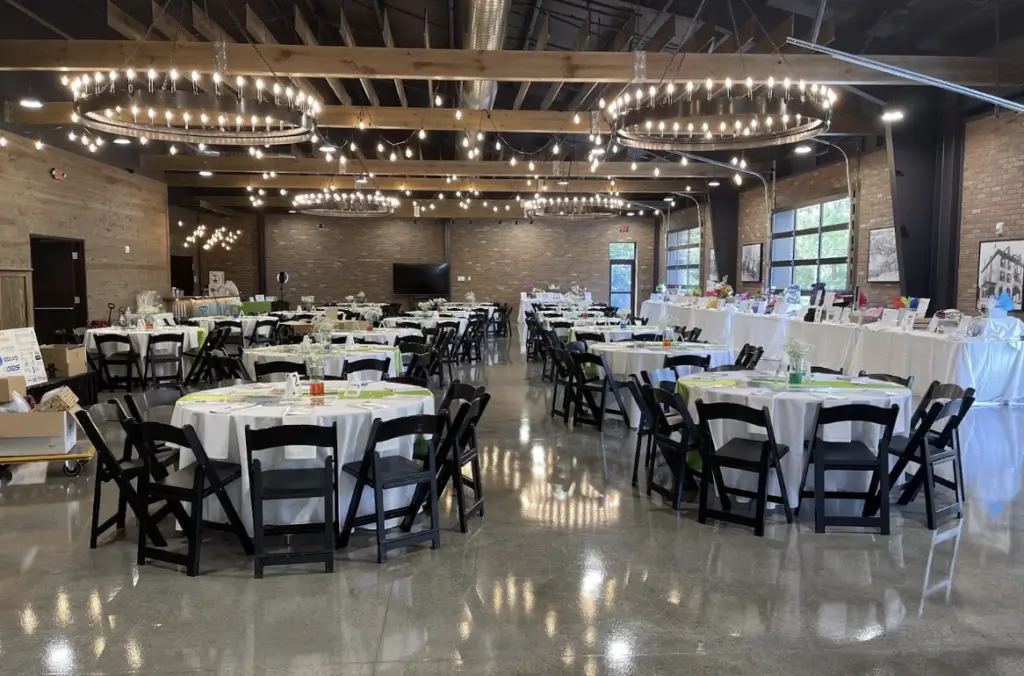 A spacious event hall with round tables and chairs