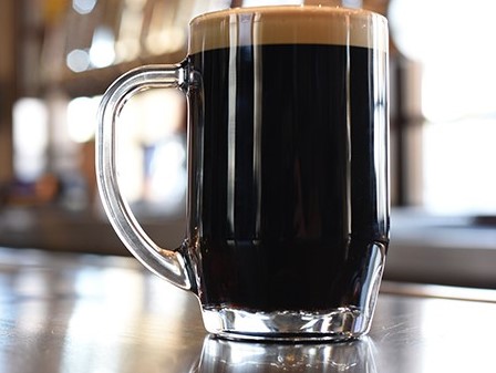 Close-up shot of a glass of dark stout beer with a foamhead.