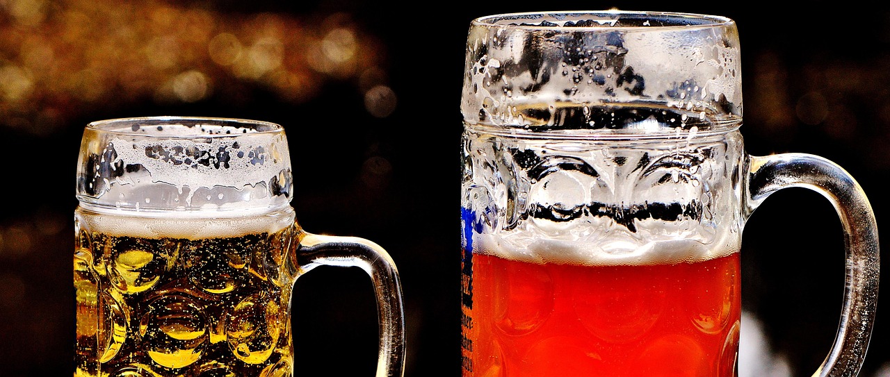 Close-up shot of two jugs of beer; one is a lager and the other an ale.