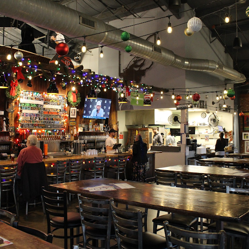 Busy taproom at Little Miami Brewing Company, with patrons enjoying drinks and live music under colorful string lights.