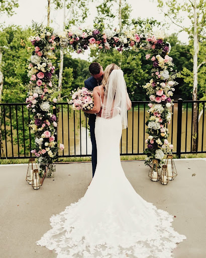 A bride and groom share a kiss under a floral arch at Little Miami Brewing Company in Cincinnati.