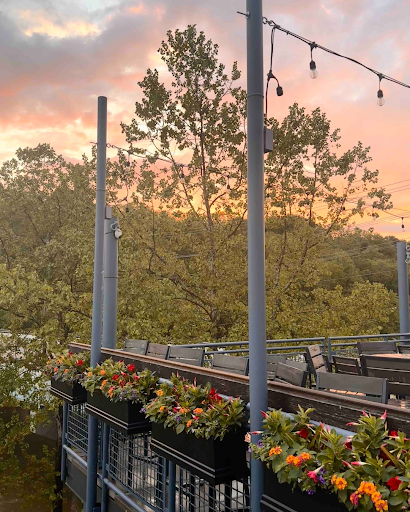 Little Miami Brewing Company’s riverside patio with flower boxes, string lights, and trees at sunset.