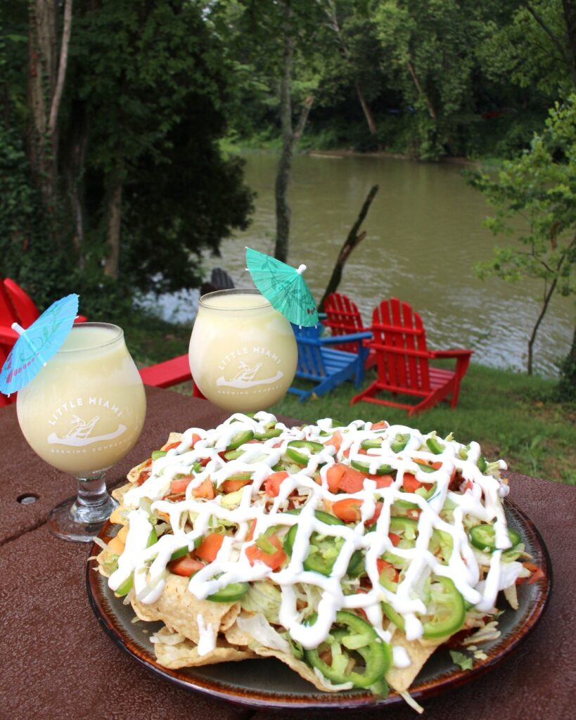 Golden nachos piled with chili, jalapeños, and beer cheese, paired with frosty Piña Coladas overlooking the Little Miami River.