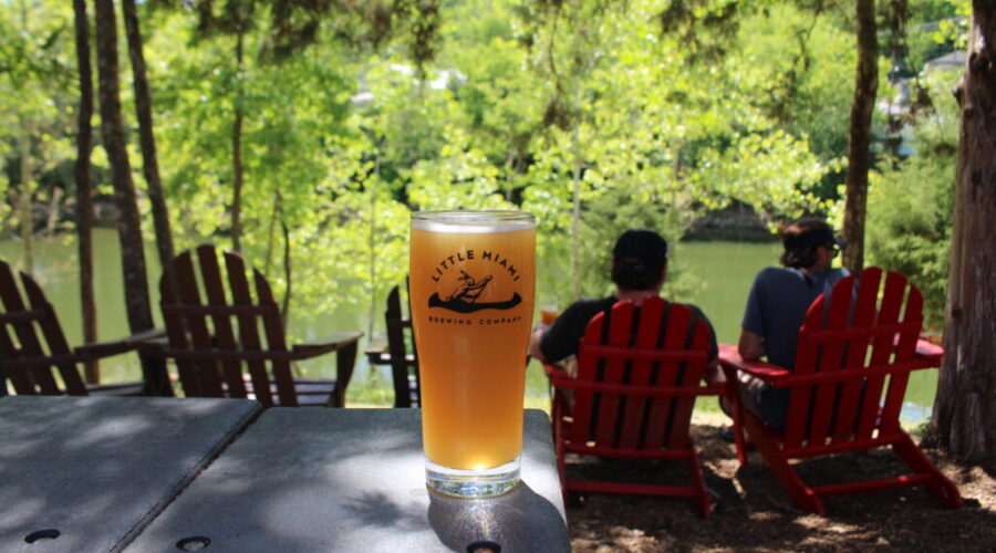 A chilled pint of My Dad’s Truck Hazy IPA on a table at Little Miami Brewing Company, with people relaxing in the background.