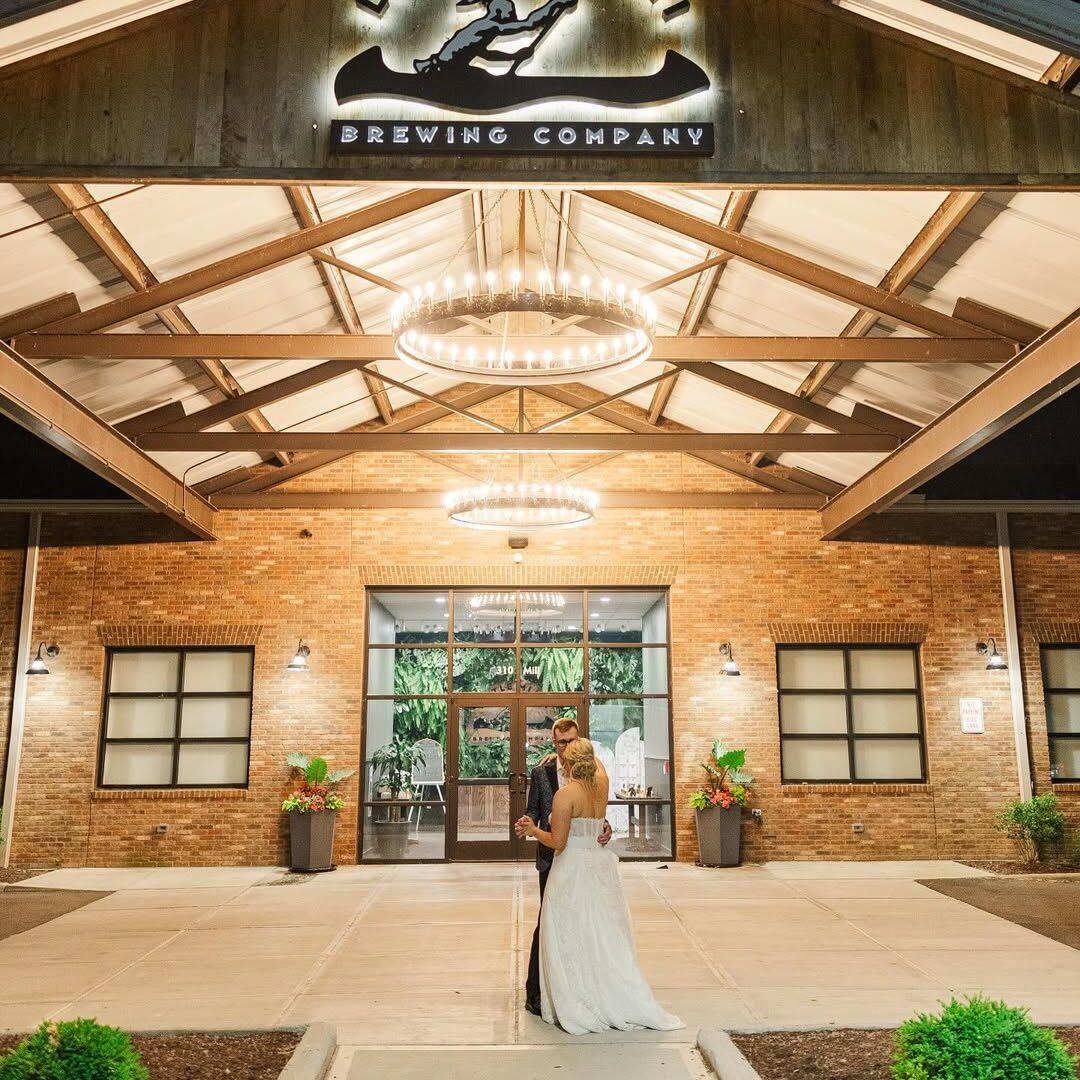 Newlywed couple dancing outside Little Miami Brewing Company at night, with the illuminated brewery logo above them.