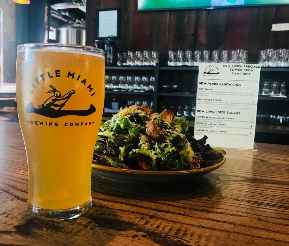 American Wheat beer at Little Miami Brewing with salad and menu board on a wooden bar.