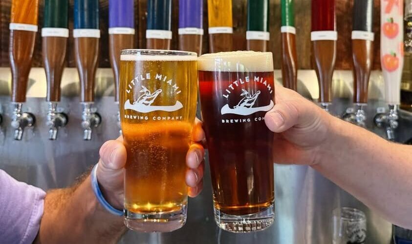 Two people clinking different beers at Little Miami Brewing Company.