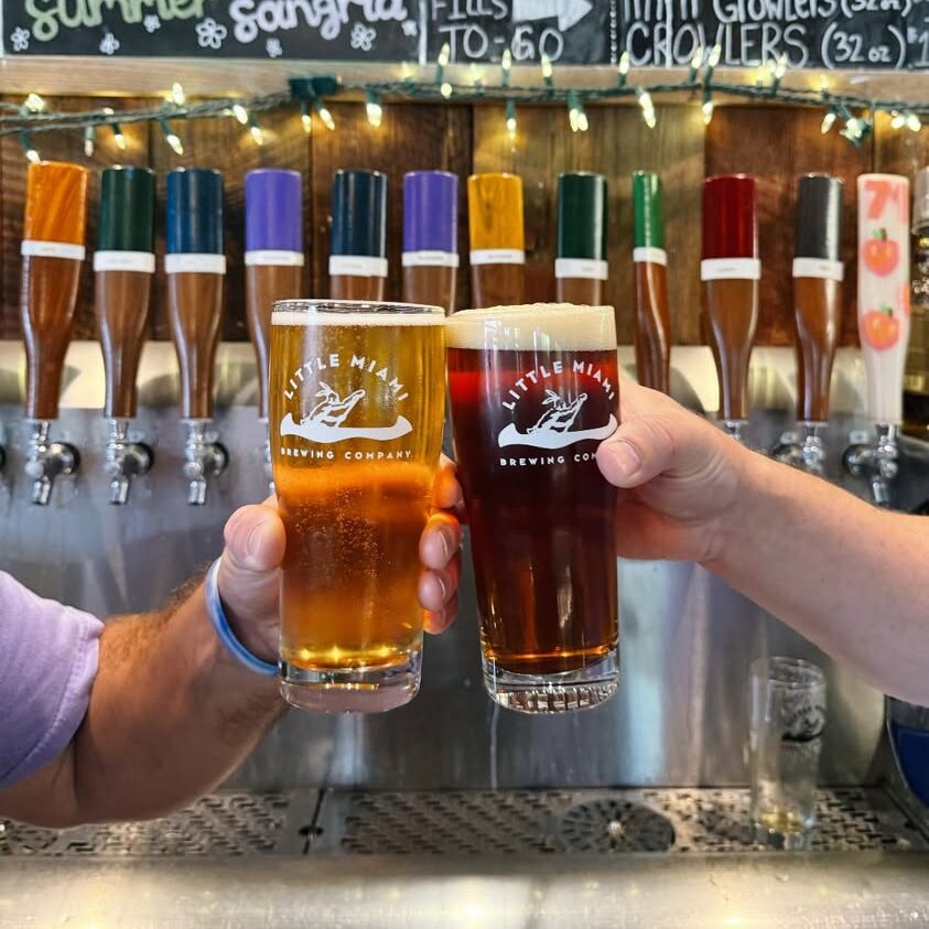 Two people clinking different beers at Little Miami Brewing Company.