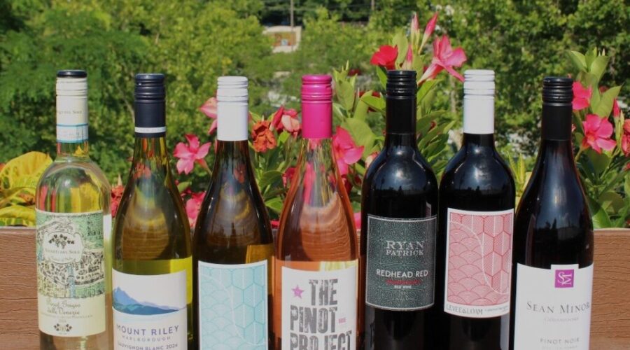 Seven wine bottles displayed side by side on a wooden outdoor table at Little Miami Brewing Company.