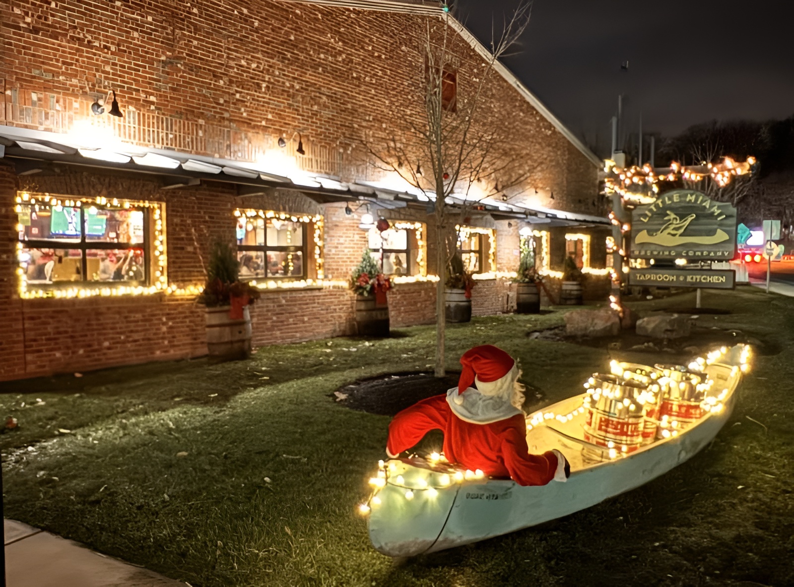 Little Miami Brewing Company exterior decorated with Christmas lights, with Santa sitting in a festive canoe out front.
