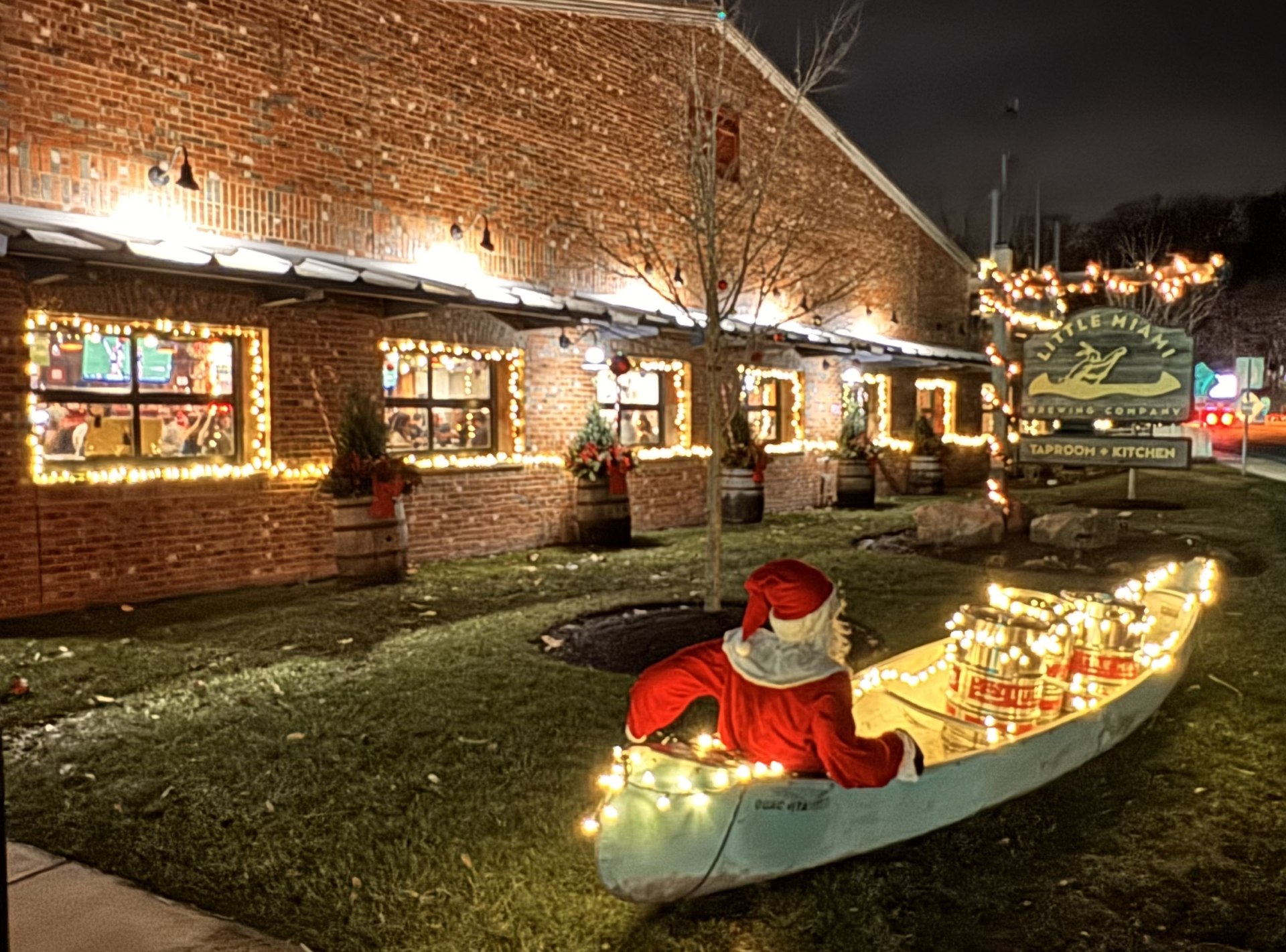 Little Miami Brewing Company exterior decorated with Christmas lights, with Santa sitting in a festive canoe out front.