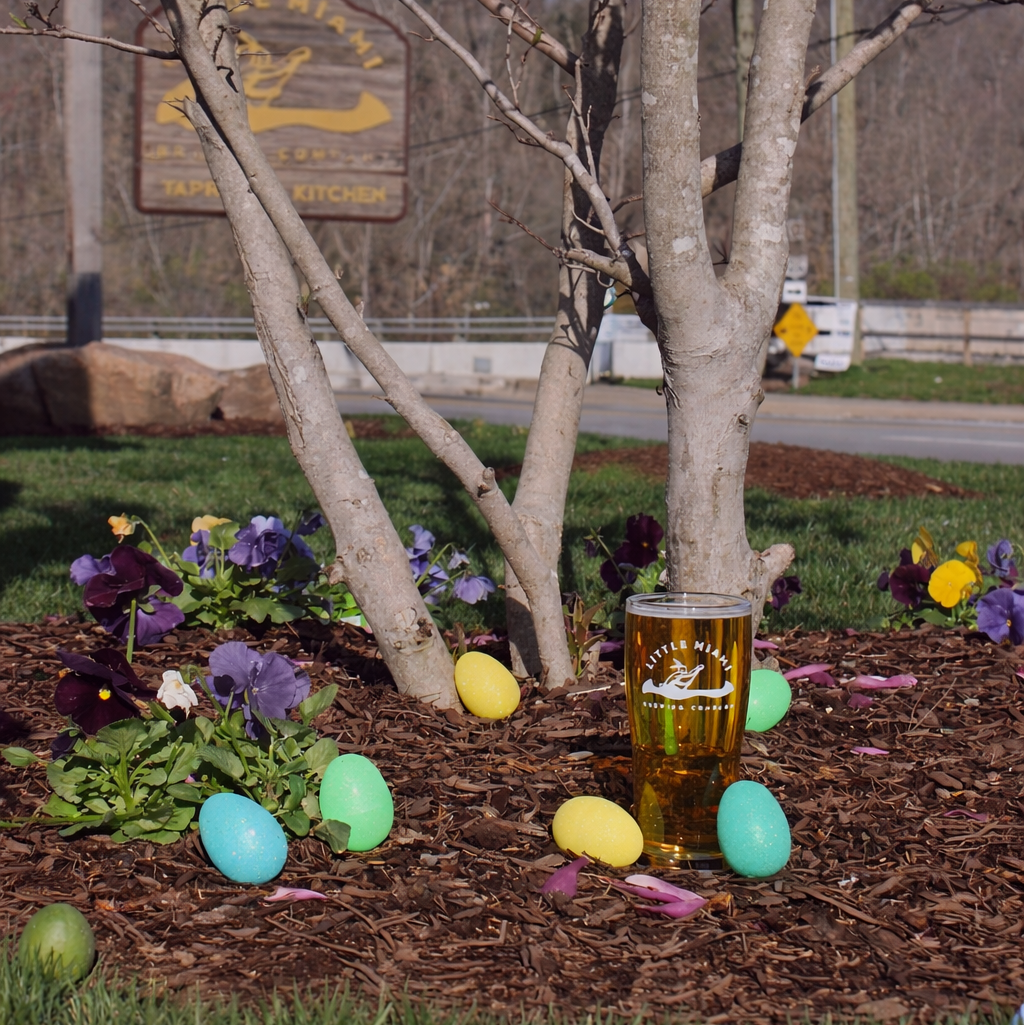 Pint of craft beer next to Easter eggs under a blooming tree at Little Miami Brewing Company.