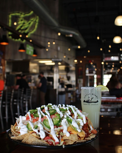 Loaded nachos topped with jalapeños and sour cream served alongside a freshly poured craft beer at Little Miami Brewing Company.