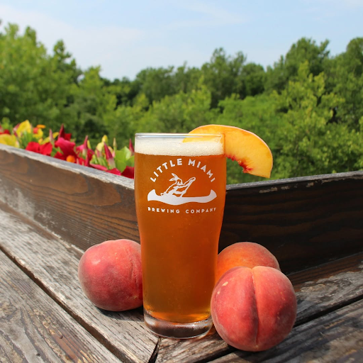 Glass of Addie's Ale, a peach wheat ale from Little Miami Brewing Company, garnished with a fresh peach slice.