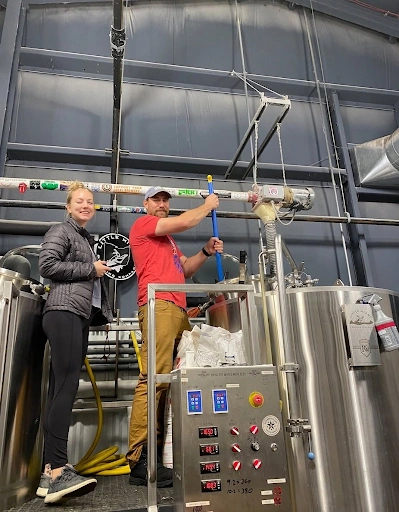 Brewers monitoring stainless steel fermentation tanks during the craft beer brewing process at Little Miami Brewing Company.