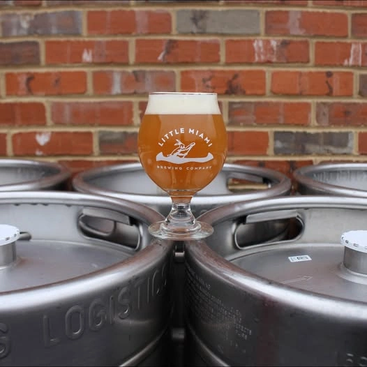 Specialty craft beer in a tasting glass resting on metal beer kegs at Little Miami Brewing Company.