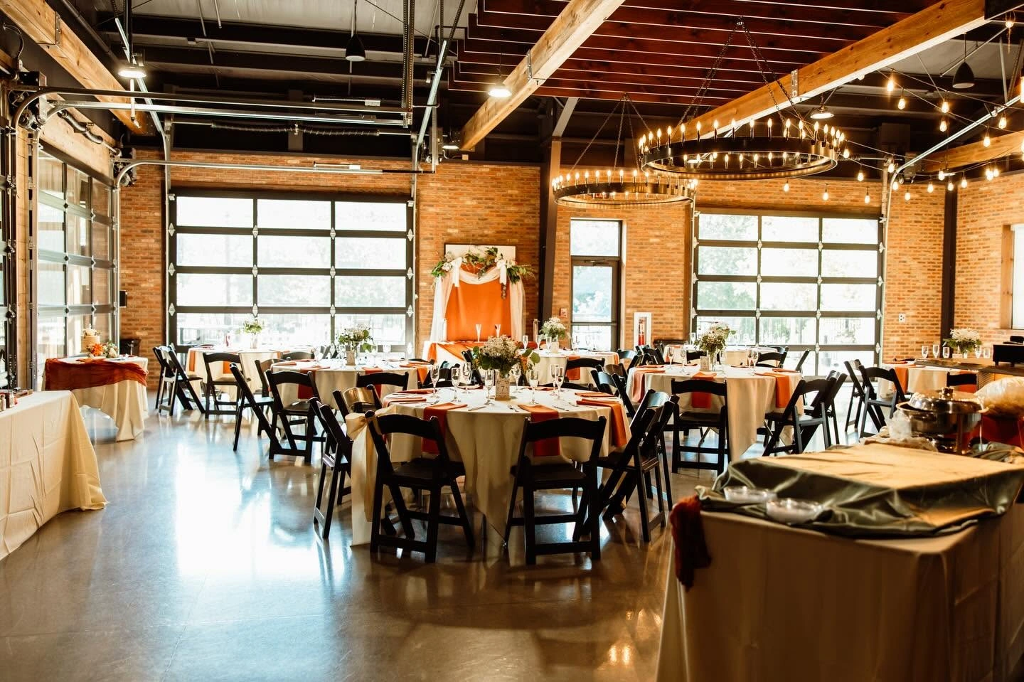 Spacious rehearsal dinner venue with exposed brick walls and round tables set up at Little Miami Brewing Company.