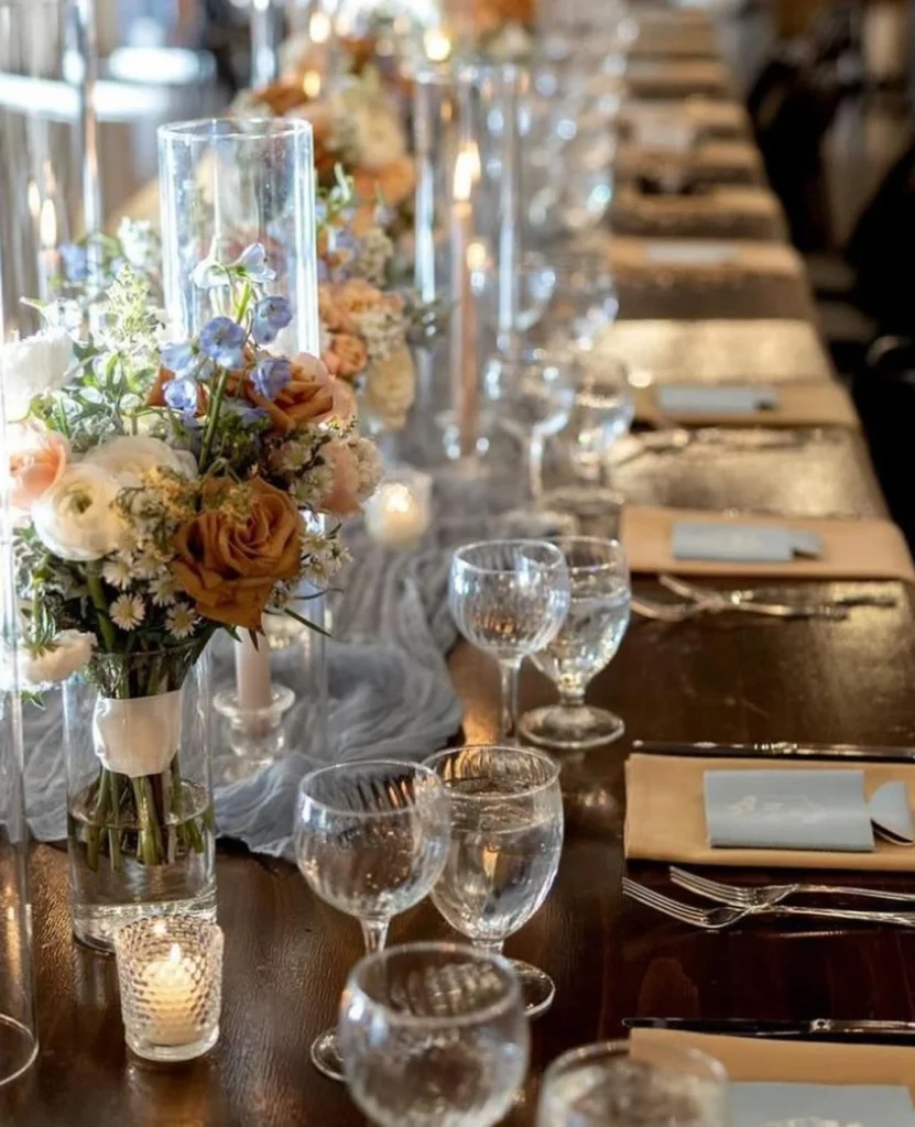 Long rehearsal dinner banquet table at Little Miami Brewing Co. decorated with candles, florals, and place settings.