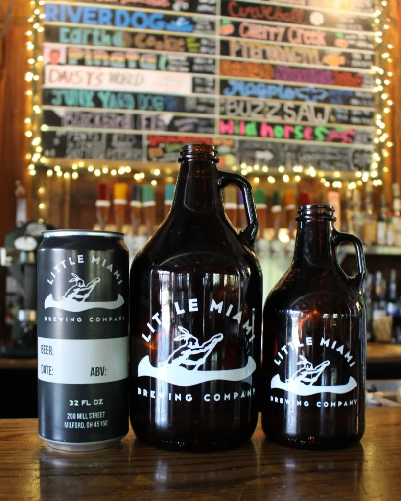 Crowler can and glass growlers displayed together in front of the tap list at Little Miami Brewing Company.