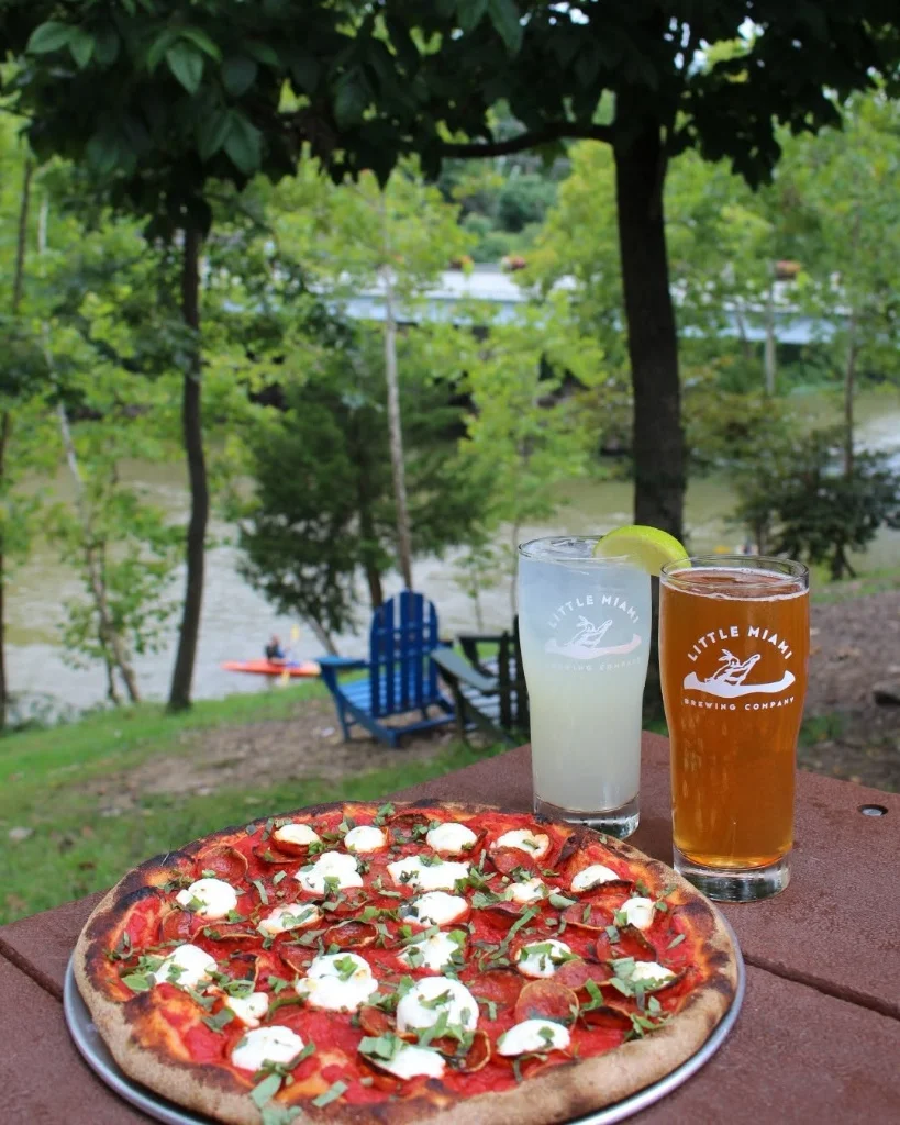 Refreshing draft beers and pizza served on a table overlooking the river at Little Miami Brewing Company.